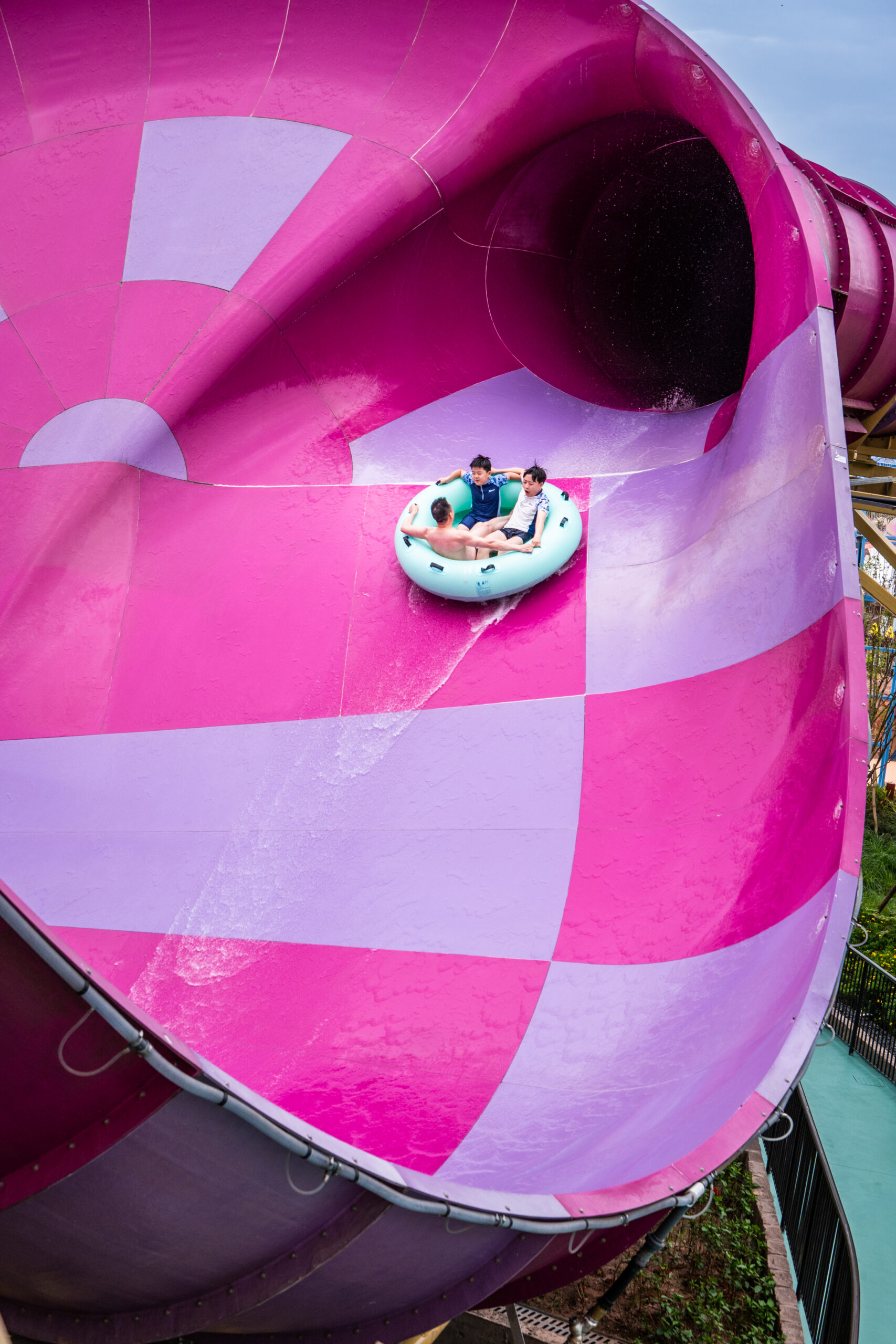 Three riders in a raft going down a water slide