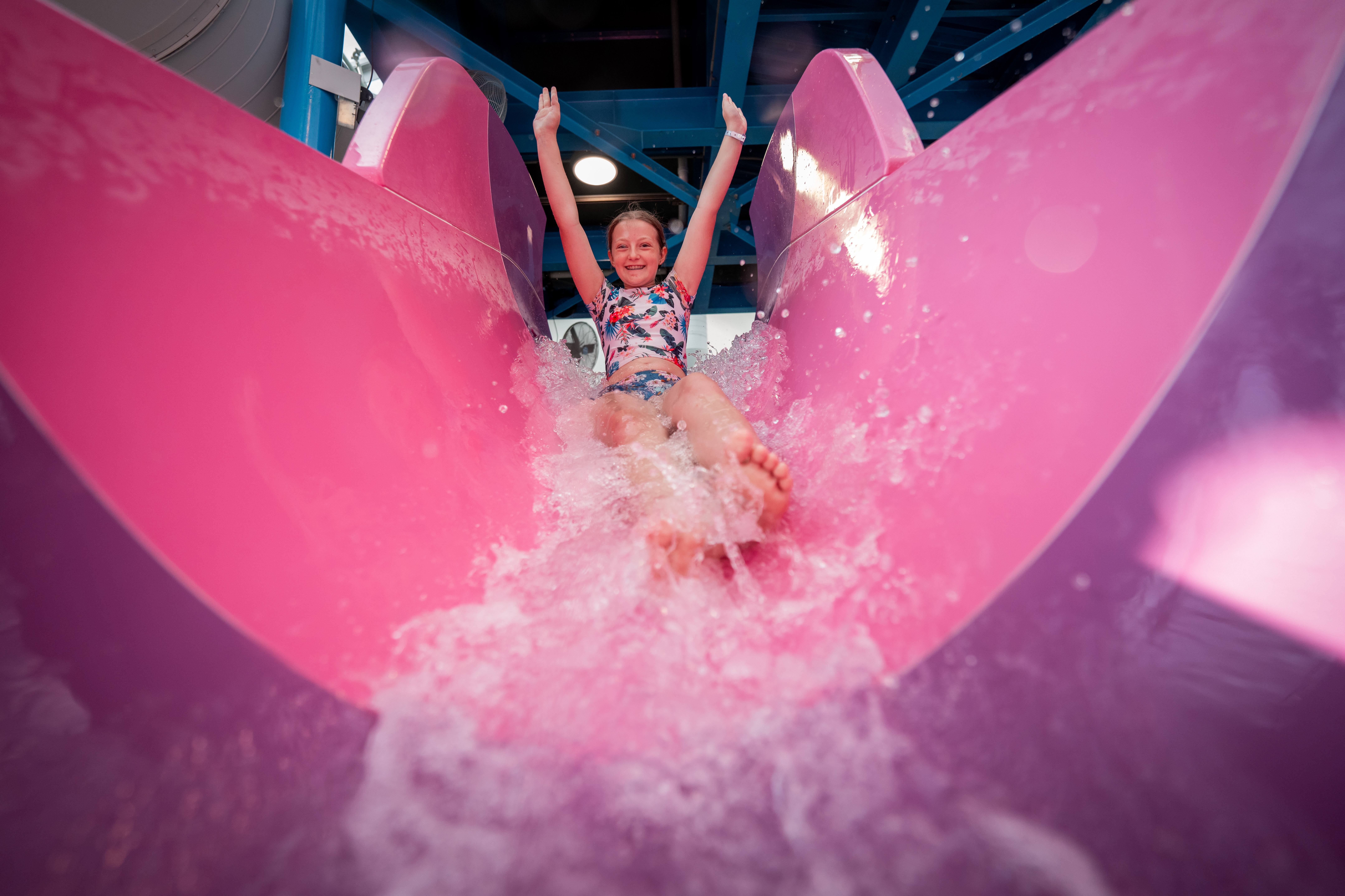 A girl going down a pink water slide