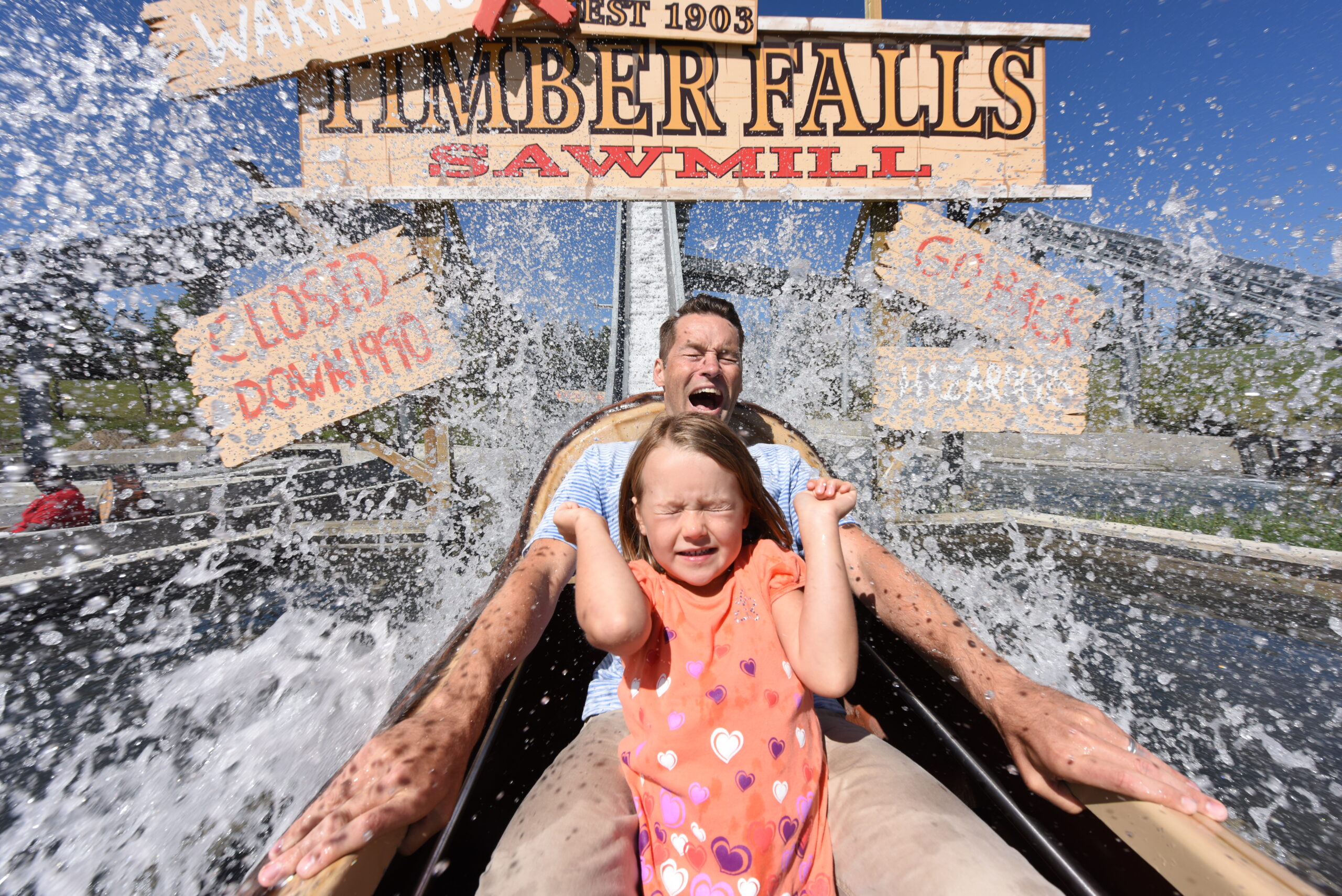 A little girl and her dad experiencing the final splash of a Log Flume water ride.