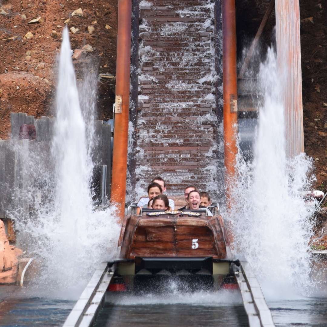 Riders in a Super Flume boat and geysers on the side