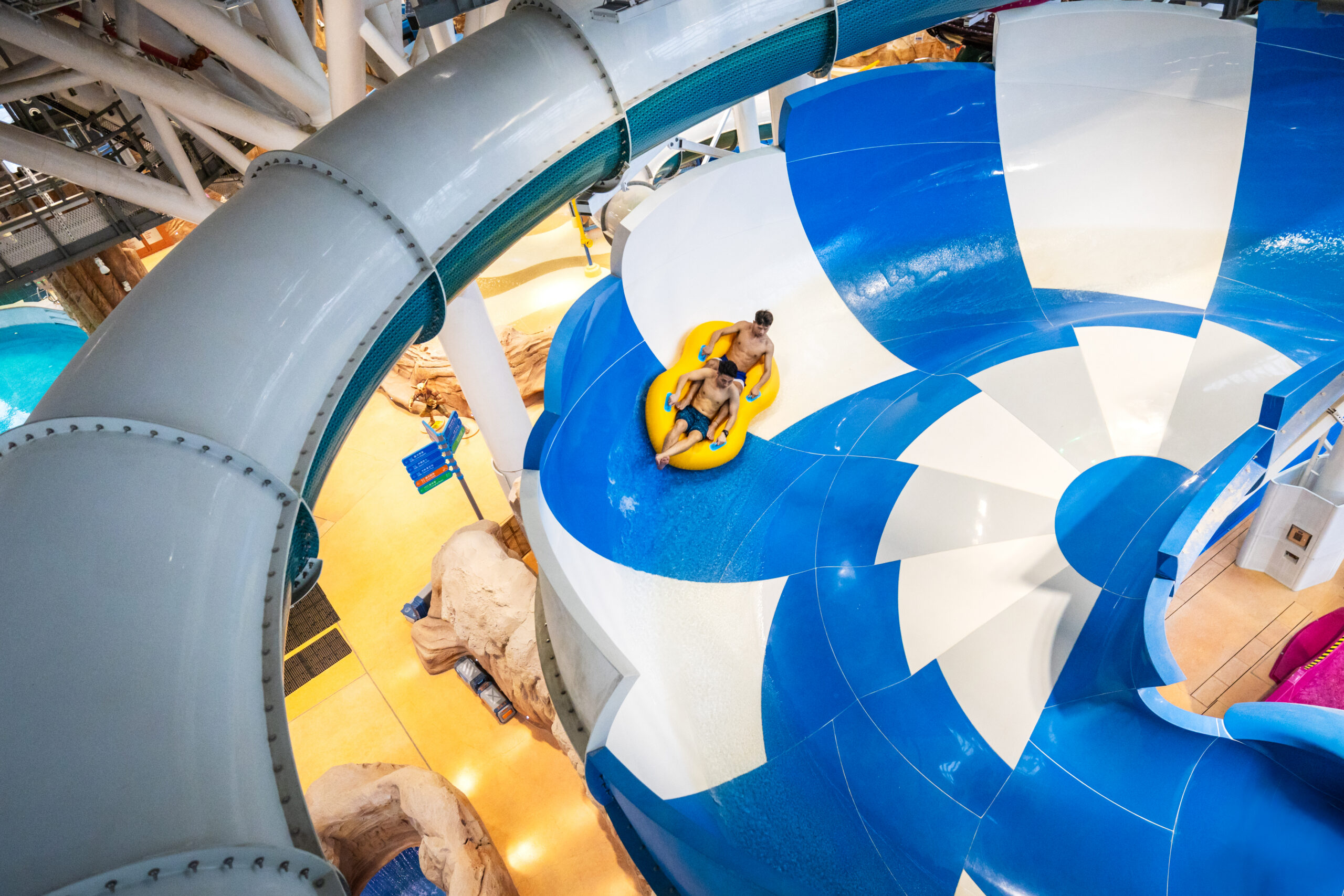 Two riders in an inner tube on a water slide in an indoor water park