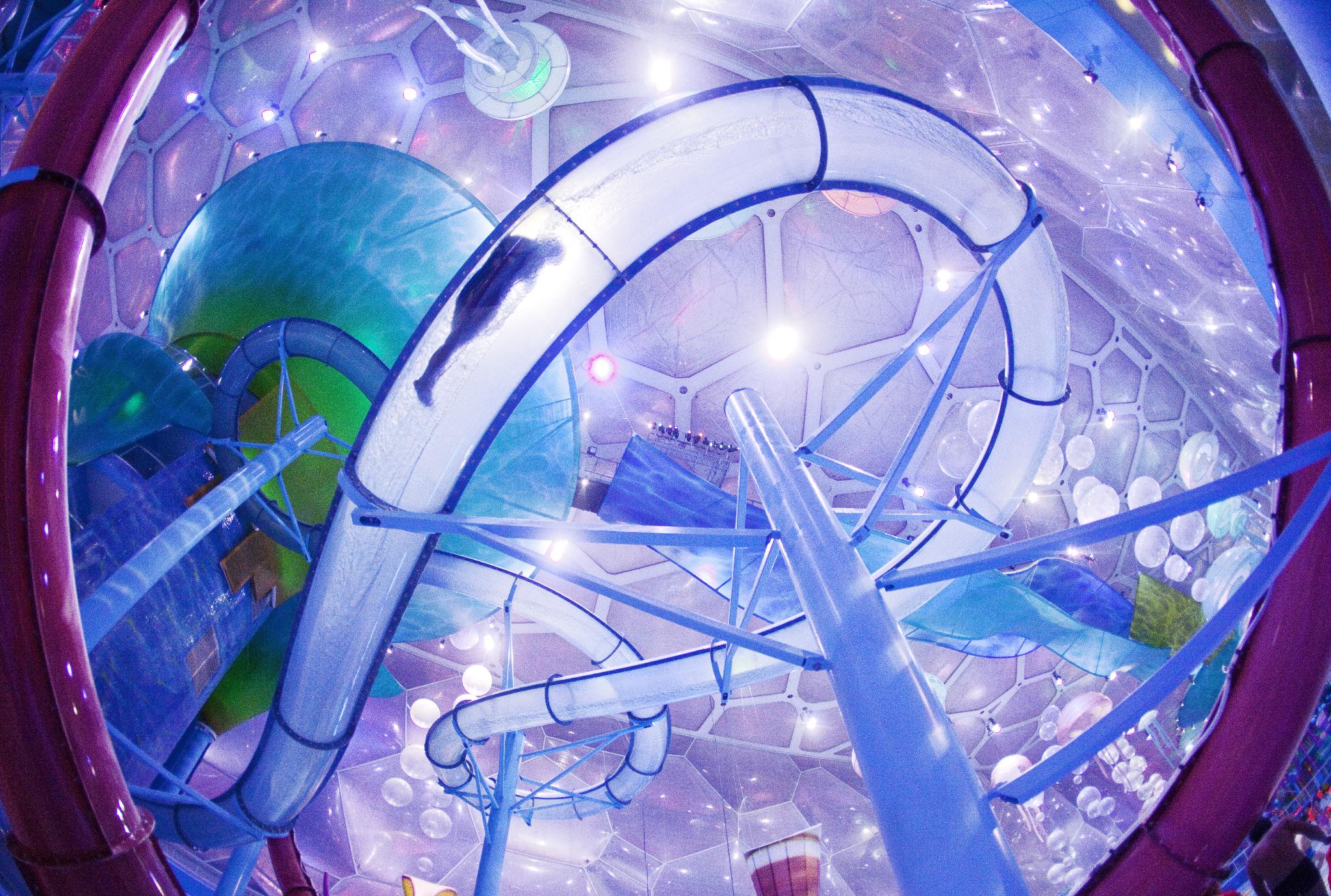 Looking up at a transparent slide, you can see a rider sliding through it at this indoor water park.