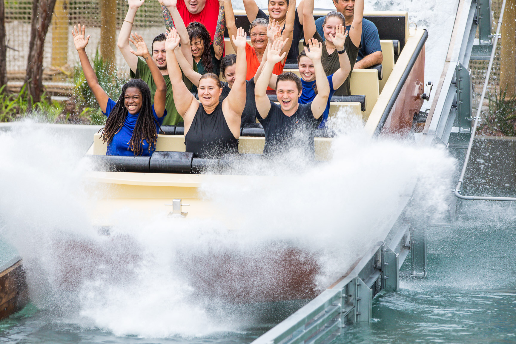 Riders with their hands up in a Shoot the Chute ride splashing down