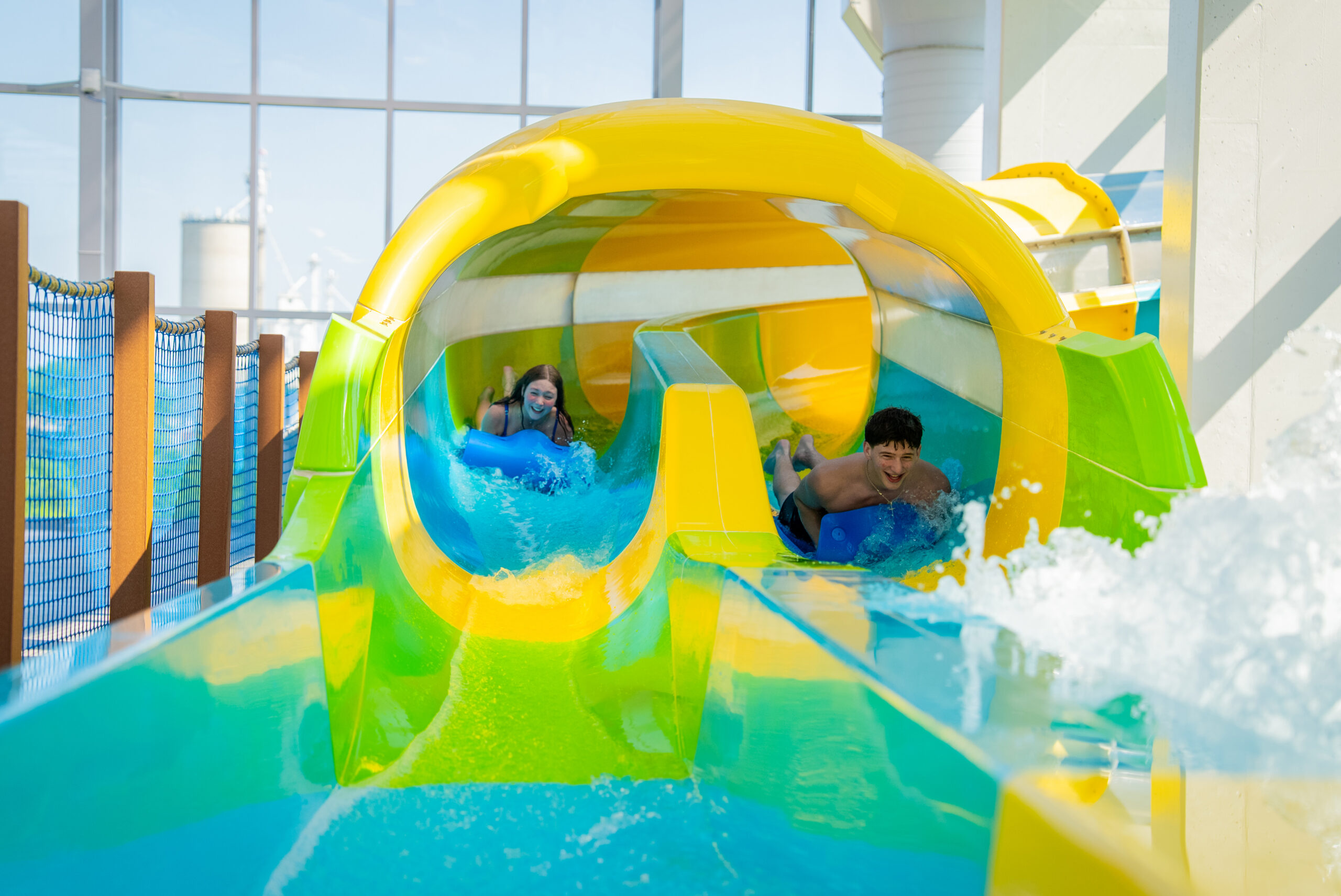 Two riders racing side by side on mats through a water slide