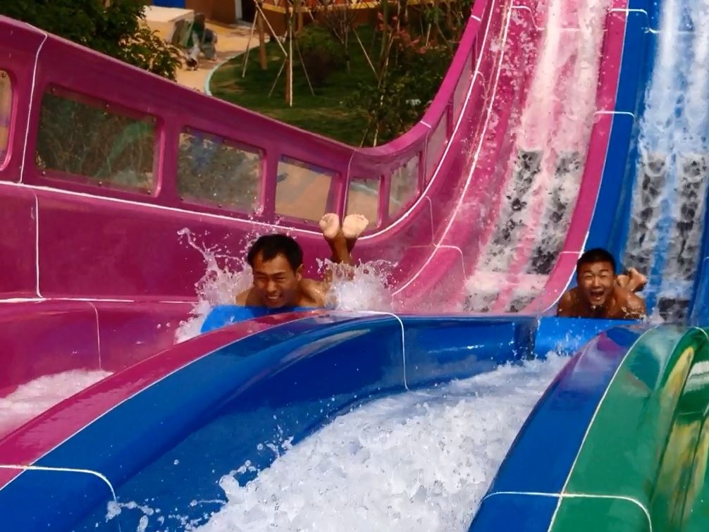 Two men on mat blaster racing water slide headfirst