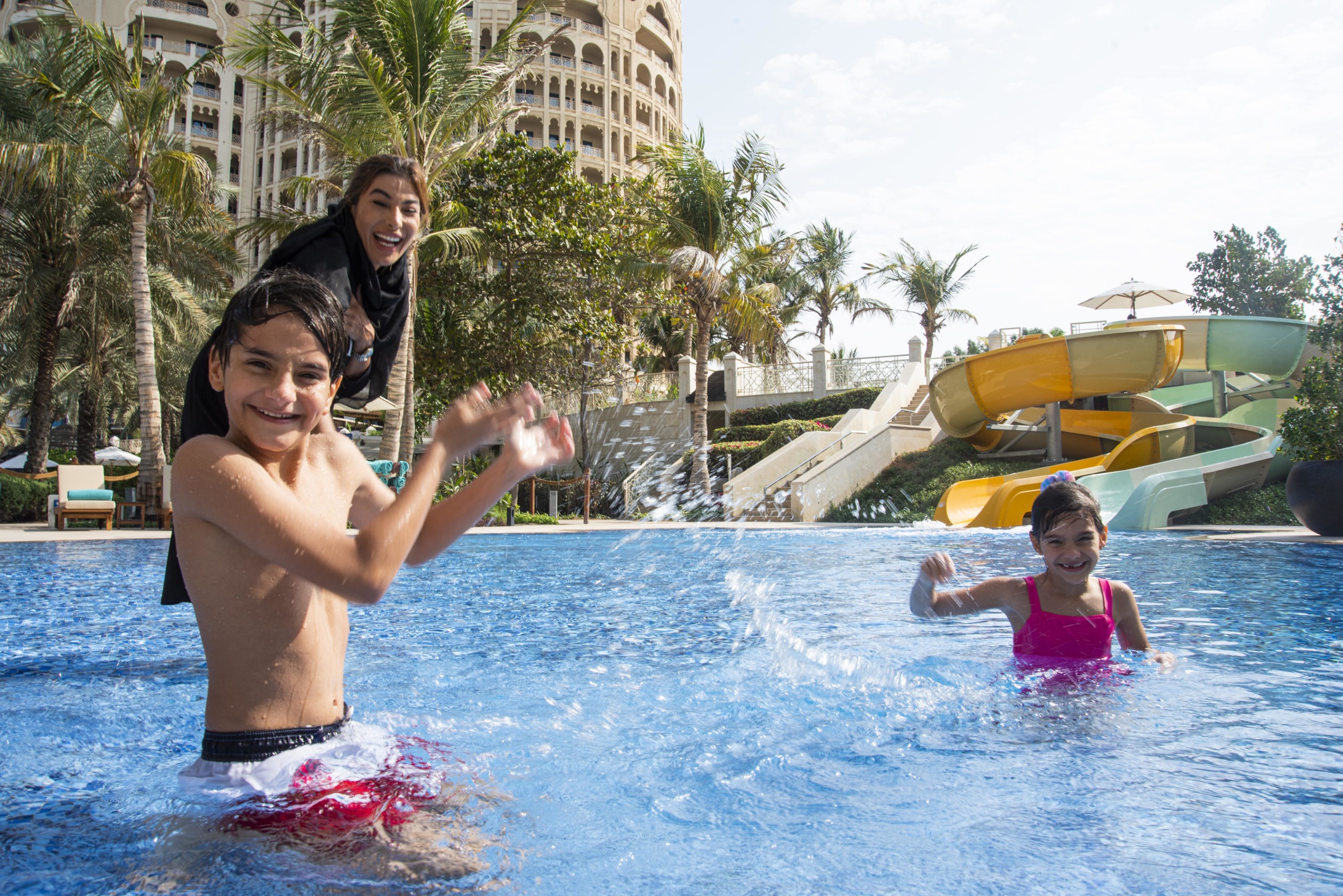 Two kids and their mother play at a hotel's aquatic kids' area