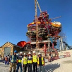 A group of men in front of a water slide tower under construction