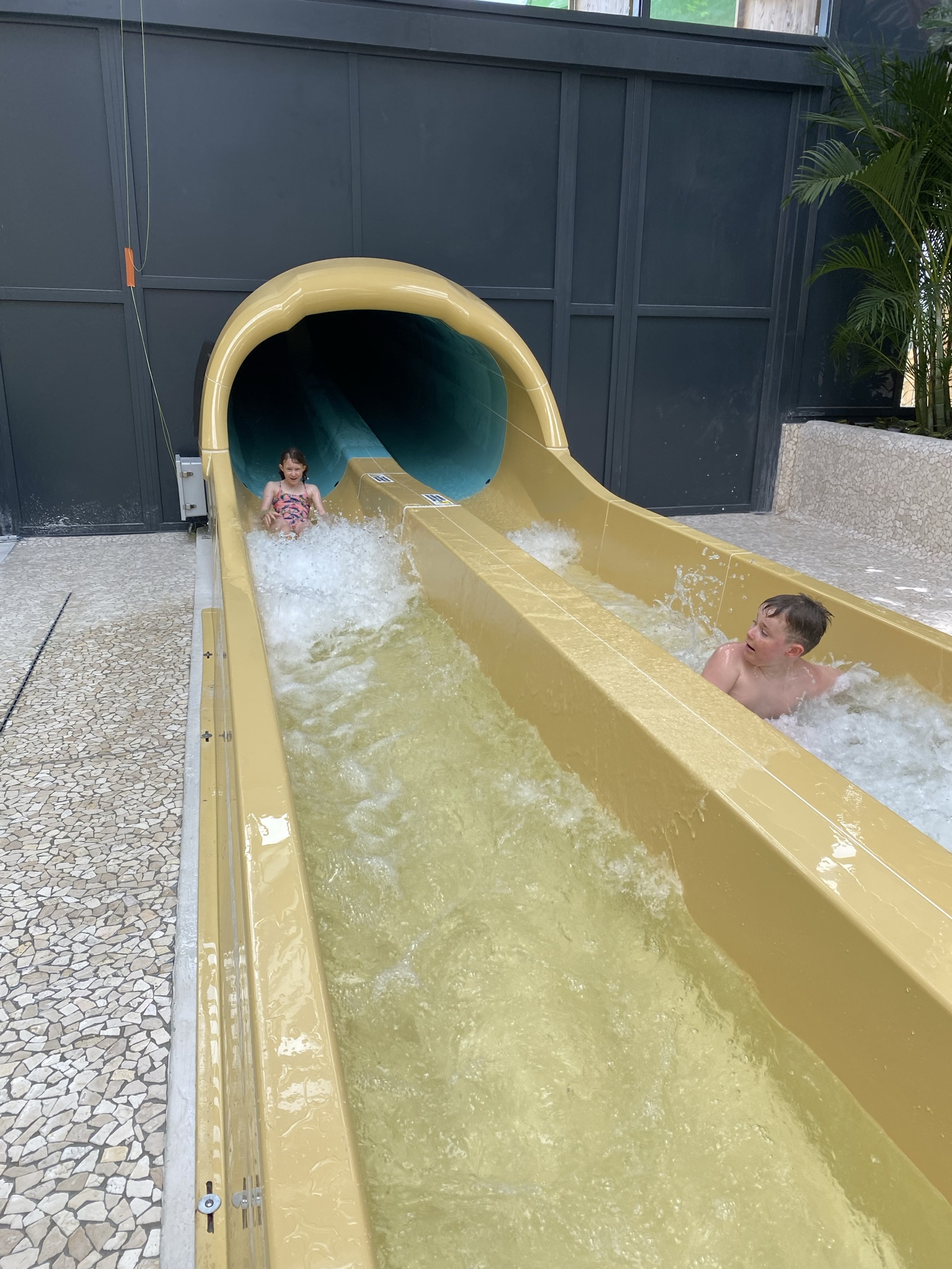 Two kids sliding down side-by-side water slide flumes