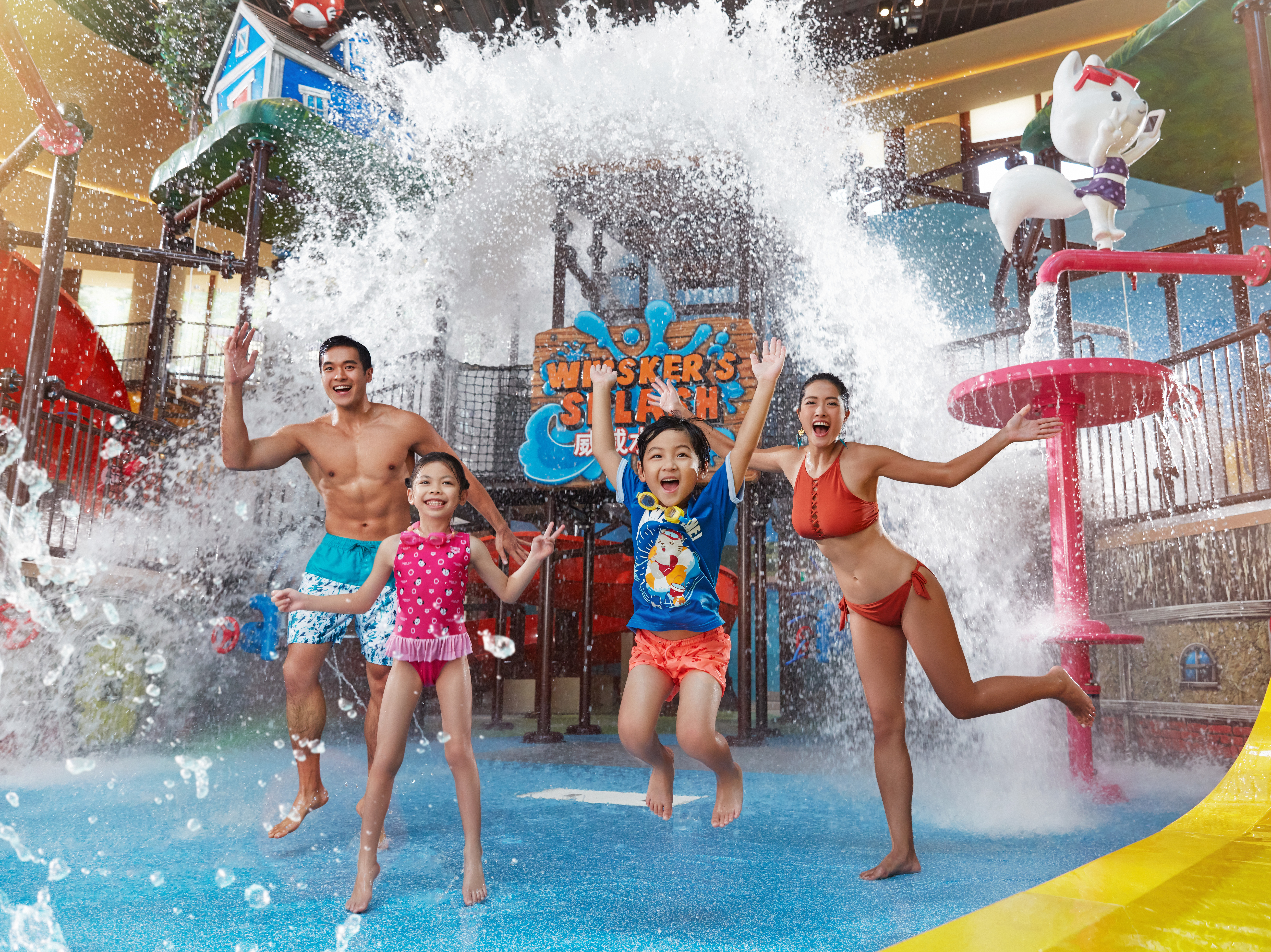 A family of four enjoying an aquatic play structure at a water park