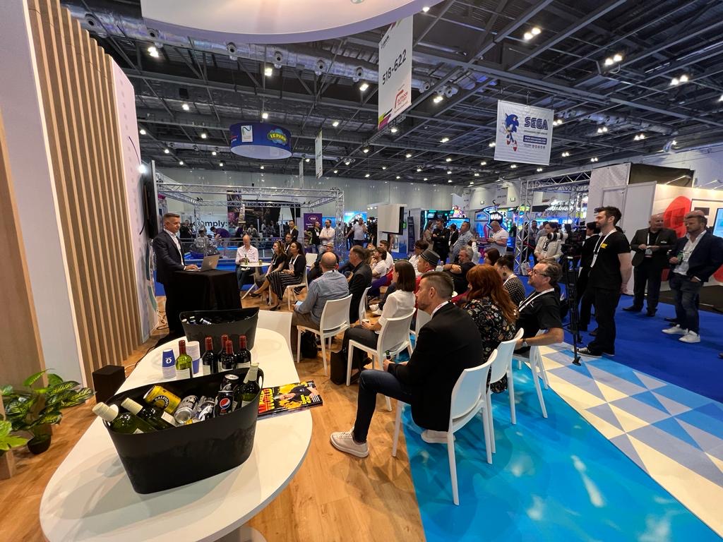 A crowd gathered in front of a speaker on the trade show floor