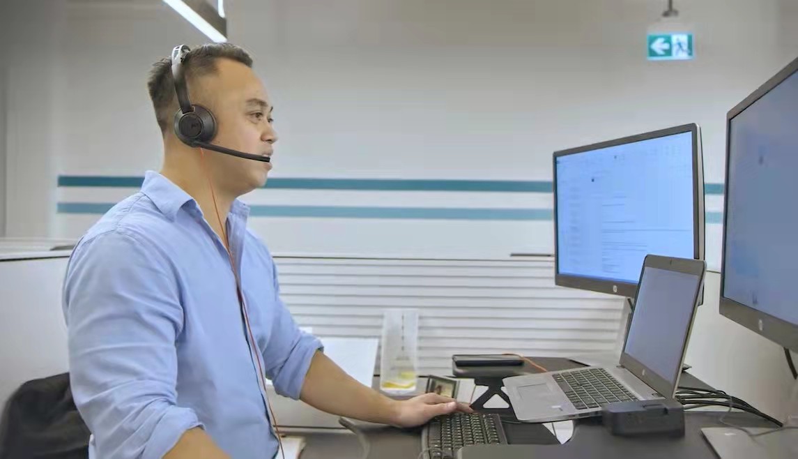 Man with headset in front of computer helping client answer questions