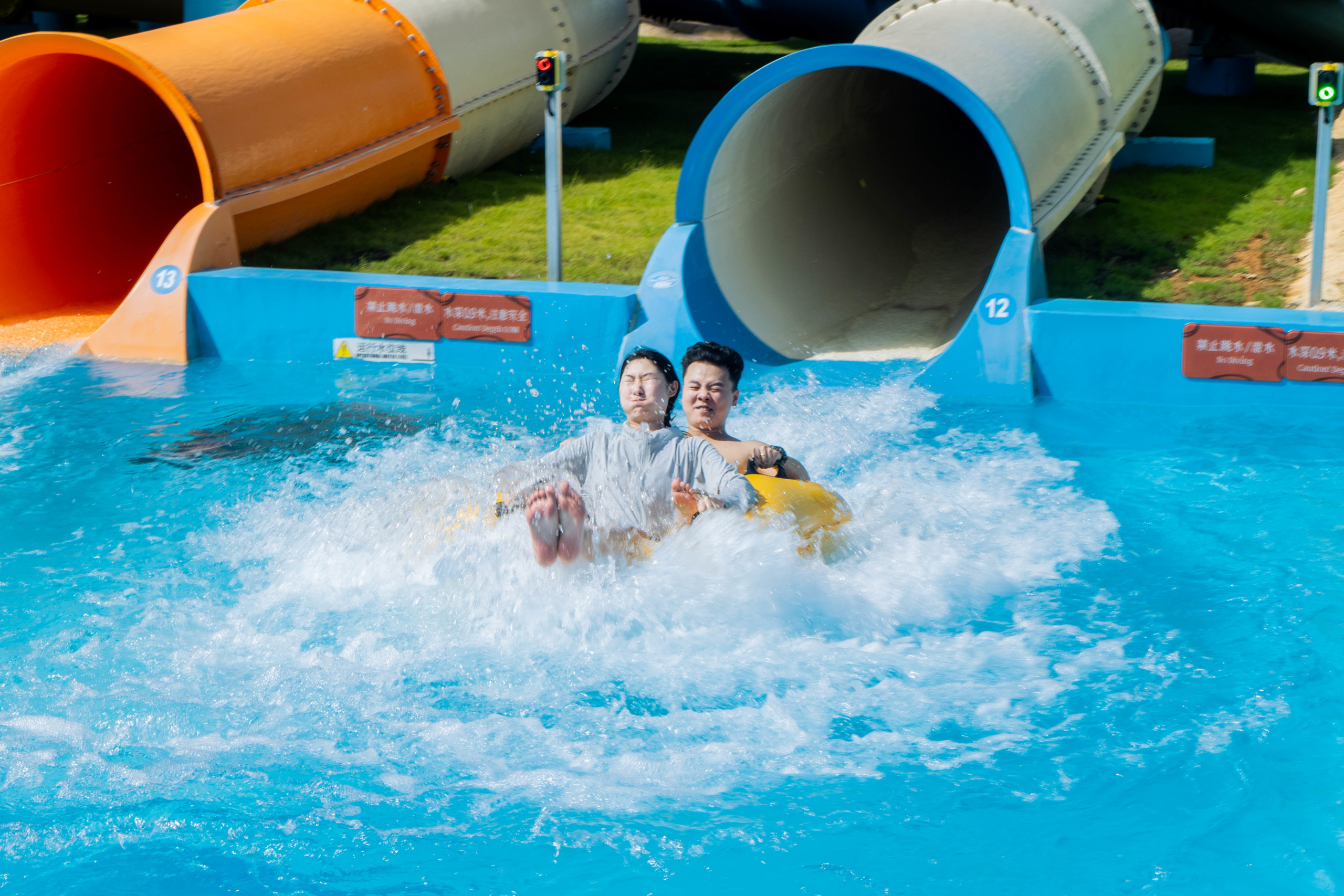 Two people in an inner tube coming out of a water slide flume