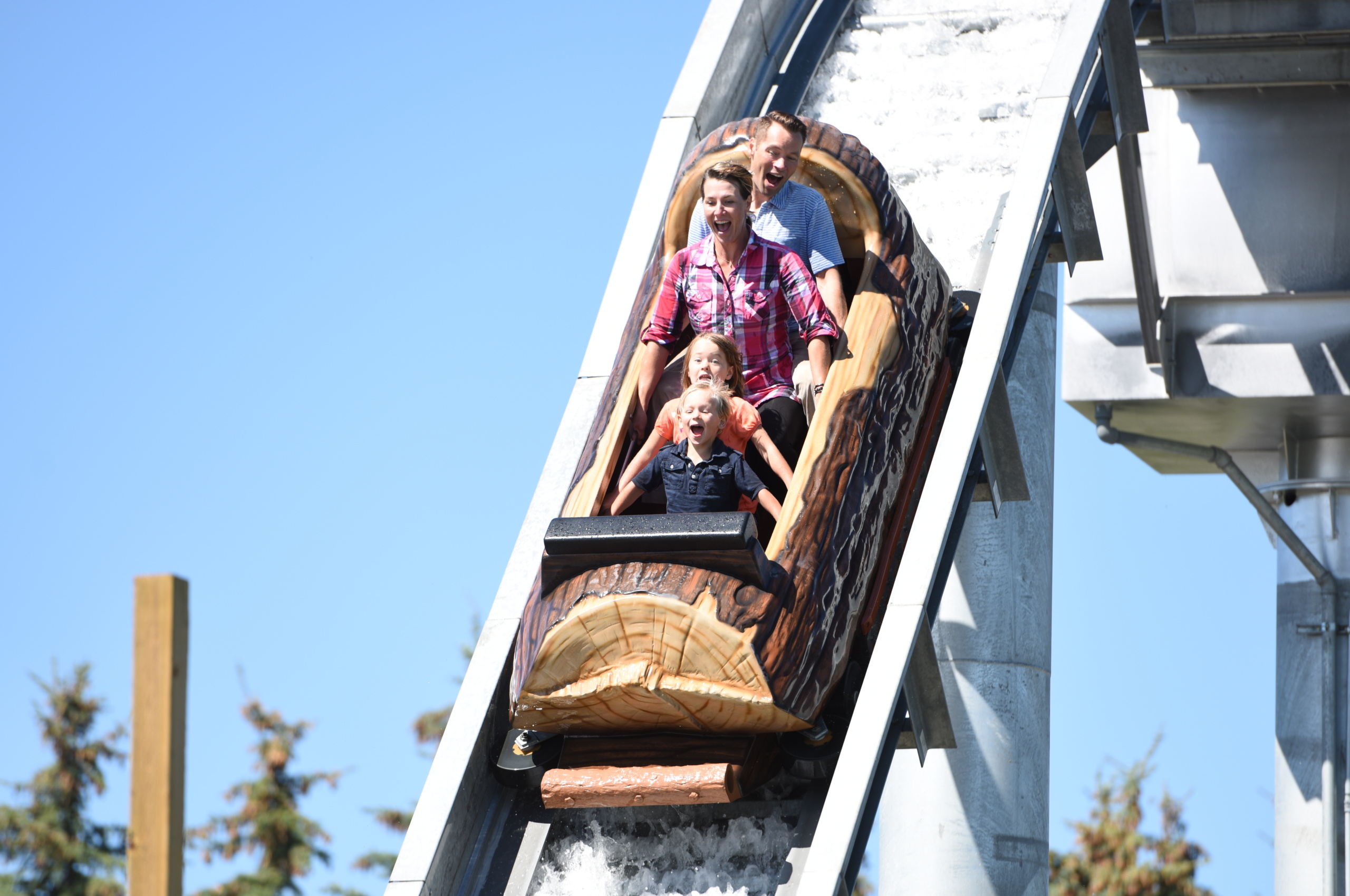 Two adults and two children in a boat going down log flume ride