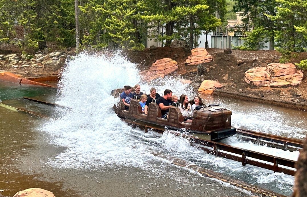 A super flume boat full of riders, splashing water in a track