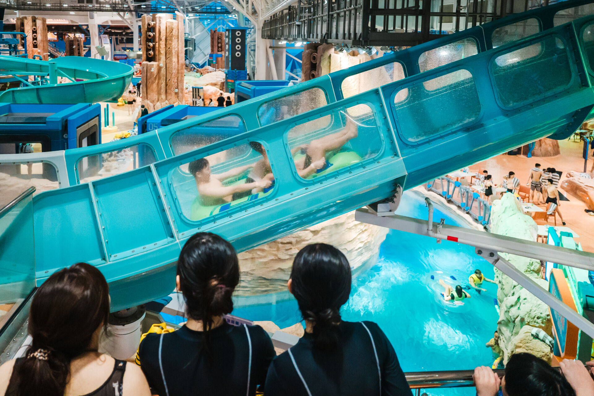 Water park guests looking at riders of a water coaster going uphill