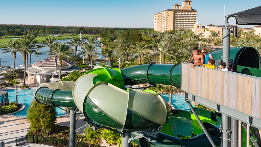 Family standing at top of water slide tower at resort