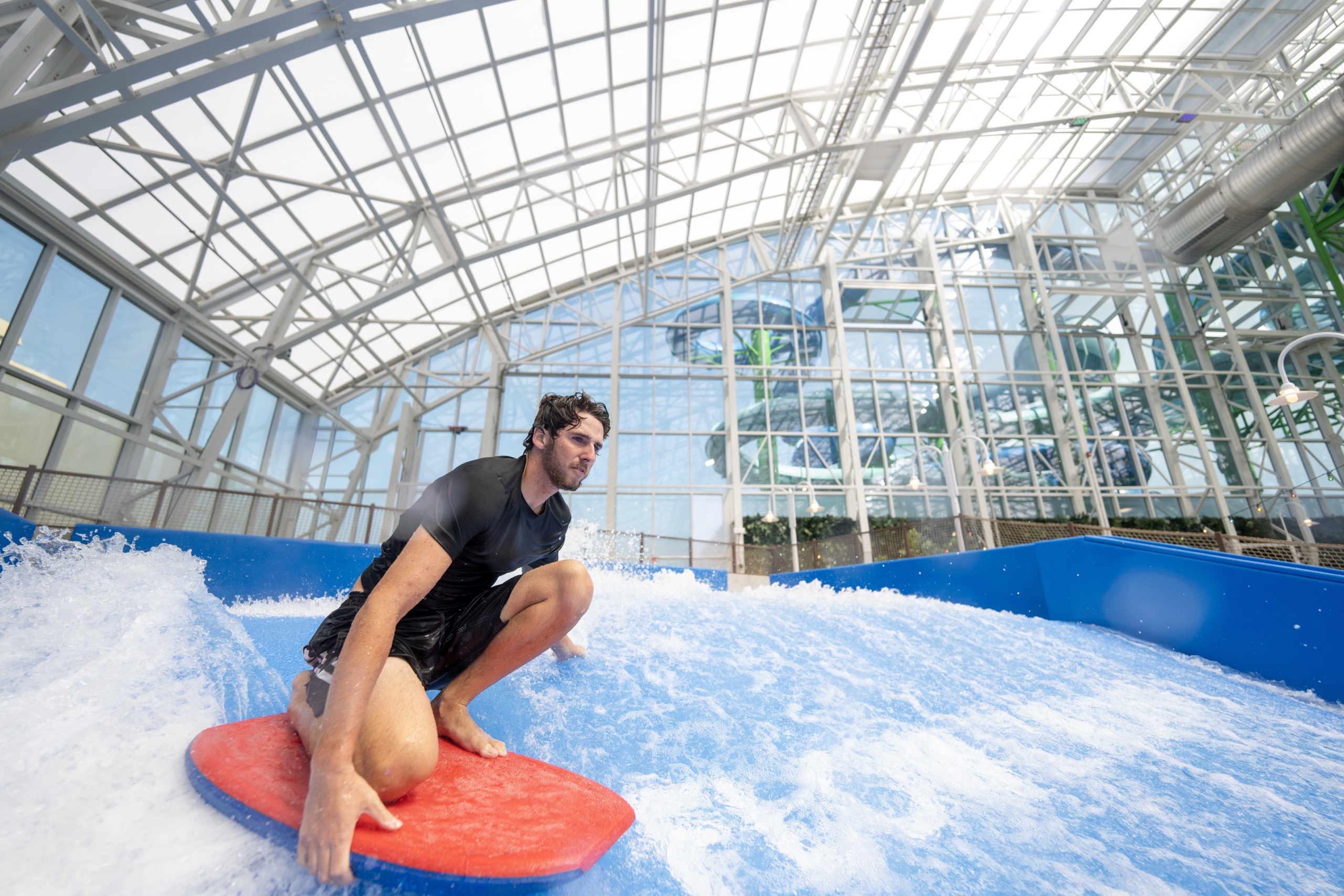 Man flowboarding on surf machine inside a water park