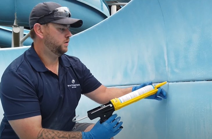 Man recaulking a water slide joint