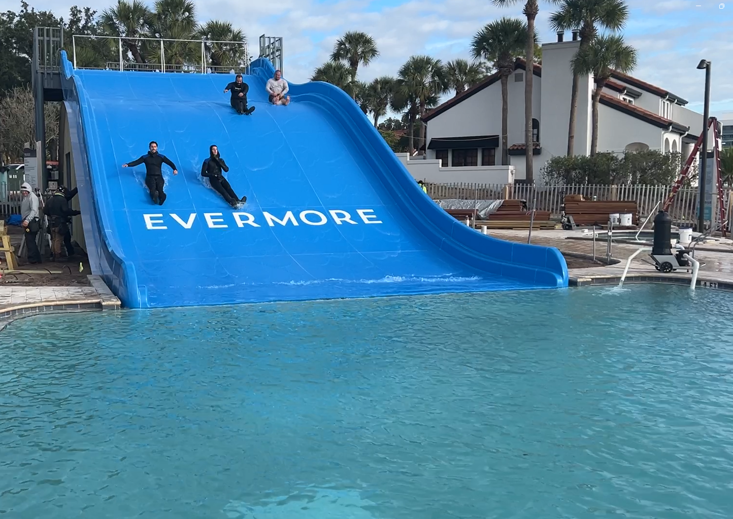 Four people going down a blue ramp slide