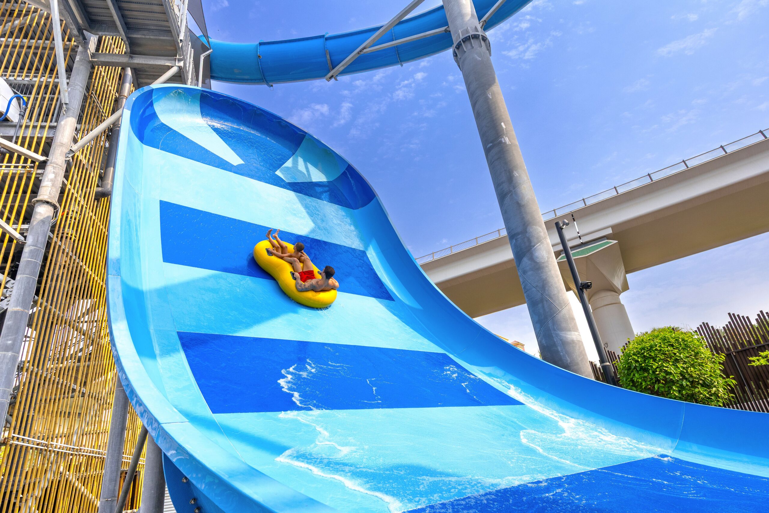 Two riders on an inner tube slide climbing up a near-vertical wall