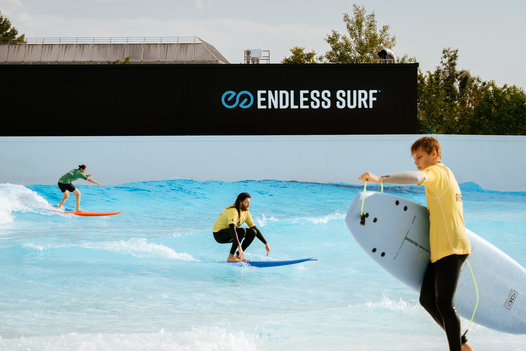 Three surfers enjoying an inland surf wave.
