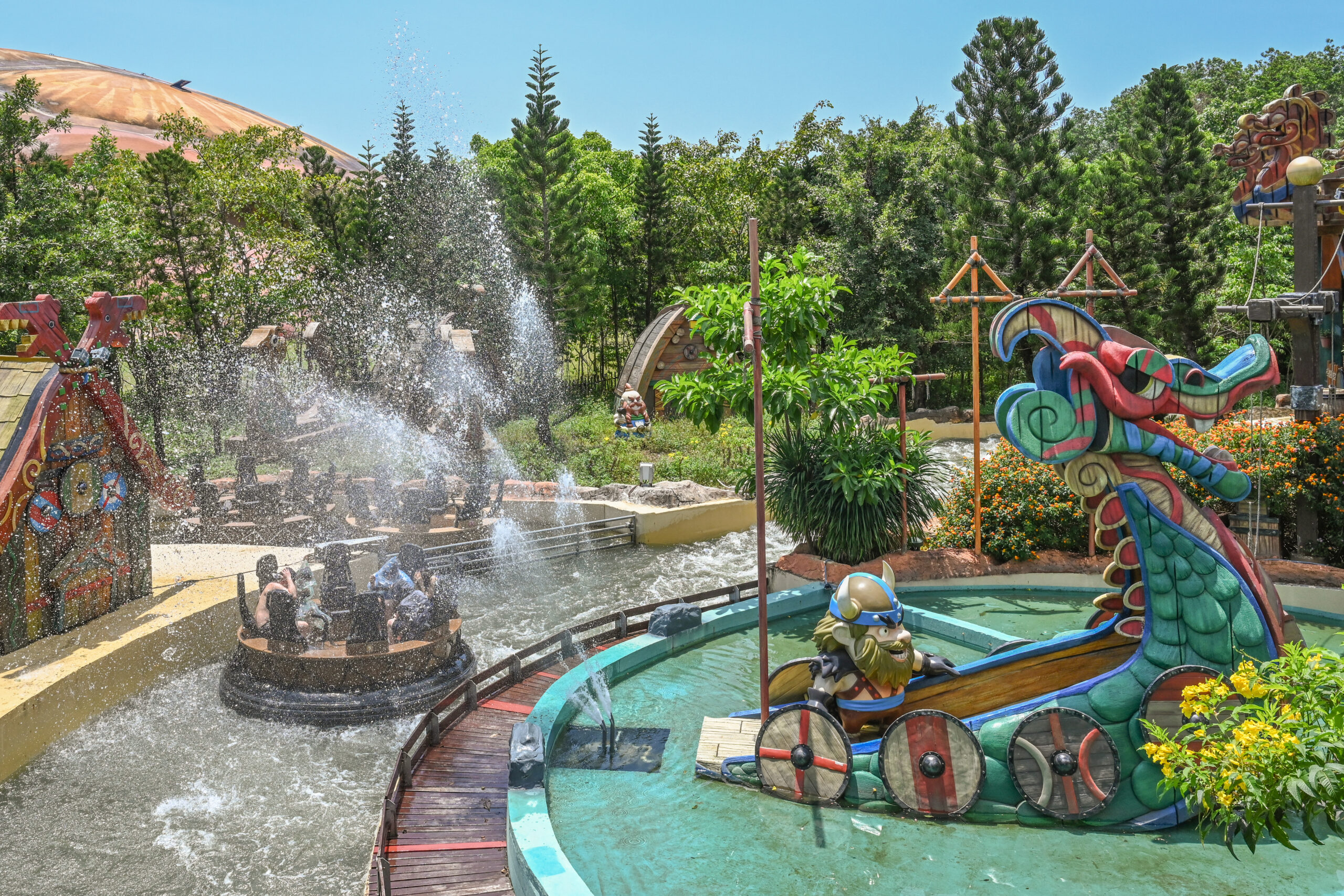 A River Raft Ride boat rocks past a Viking ship while avoiding spraying water.