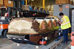 A man working on a super flume boat inside a shop