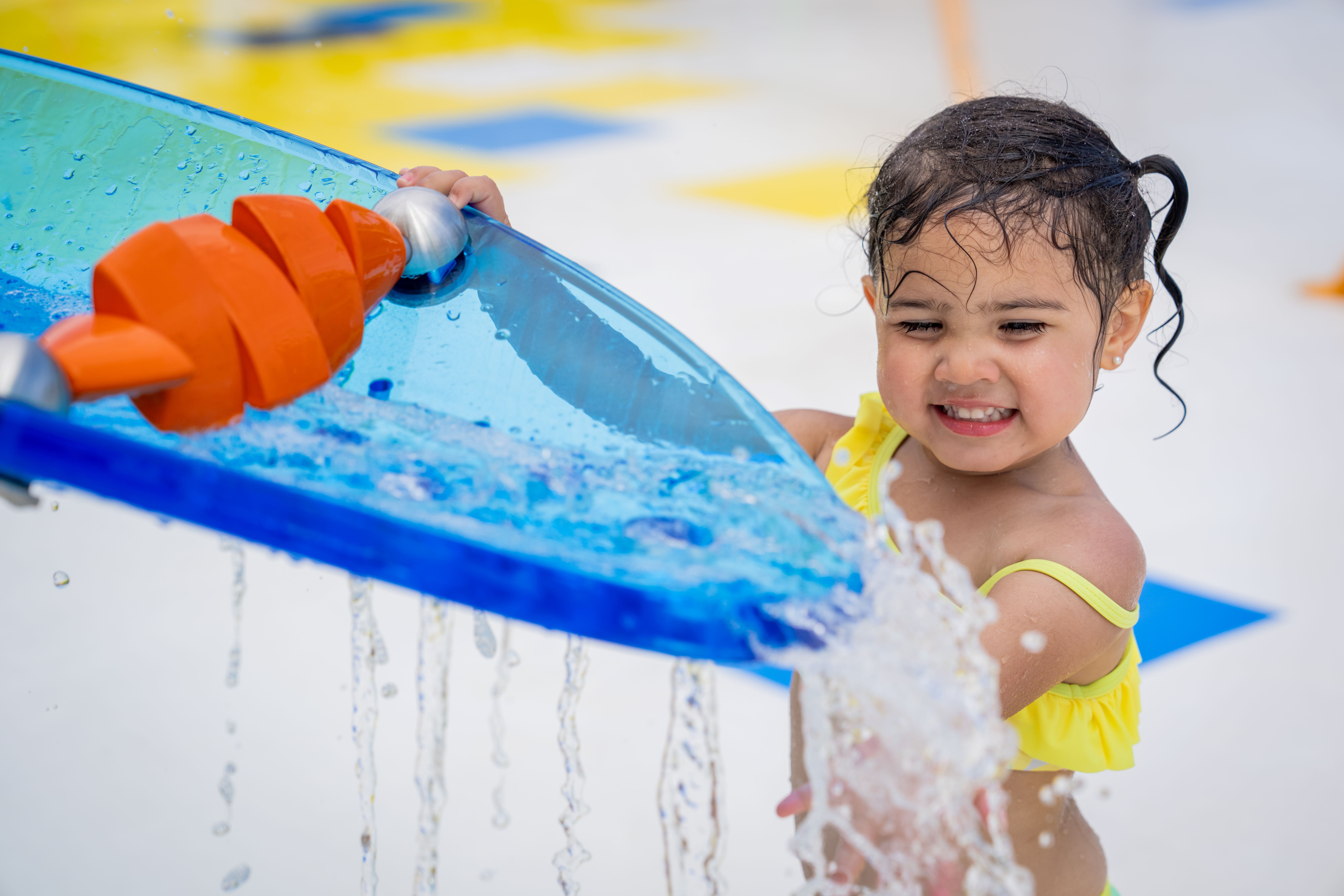 A little girl playing with a water park splash toy