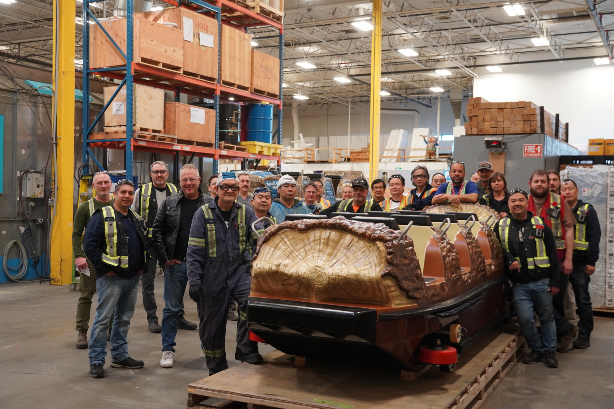 A group of people surrounding a Super Flume boat in a workshop