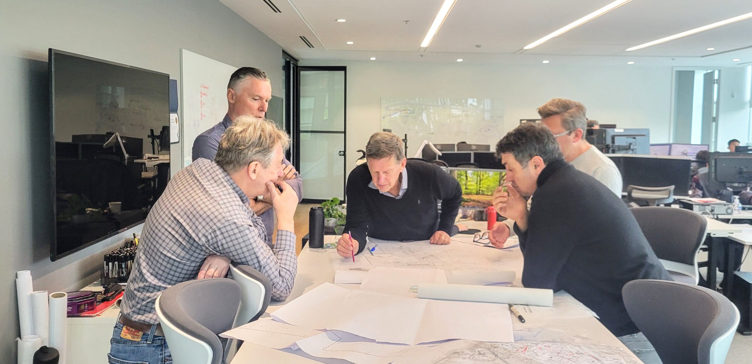 A group of men working over papers at a table