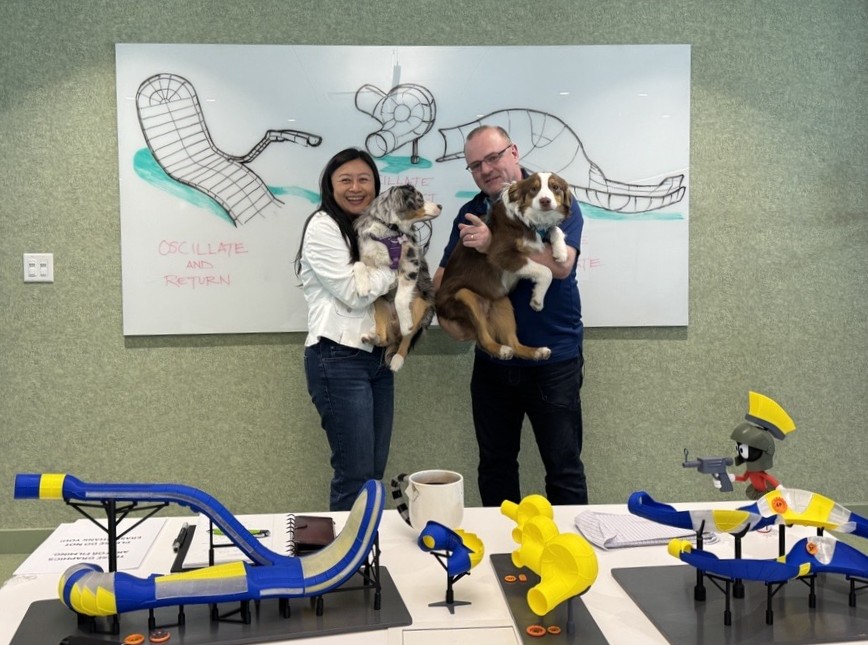 Two people each holding a dog in the office