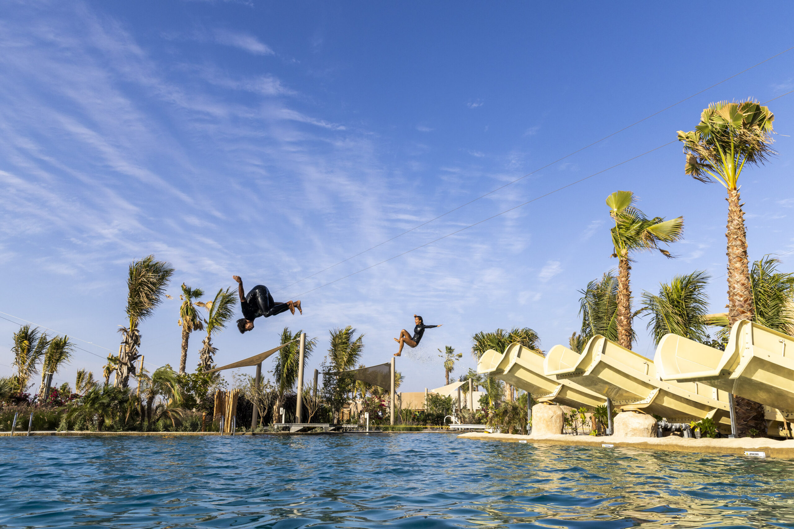 Person doing back flip in the air flying off one of three beige water slides