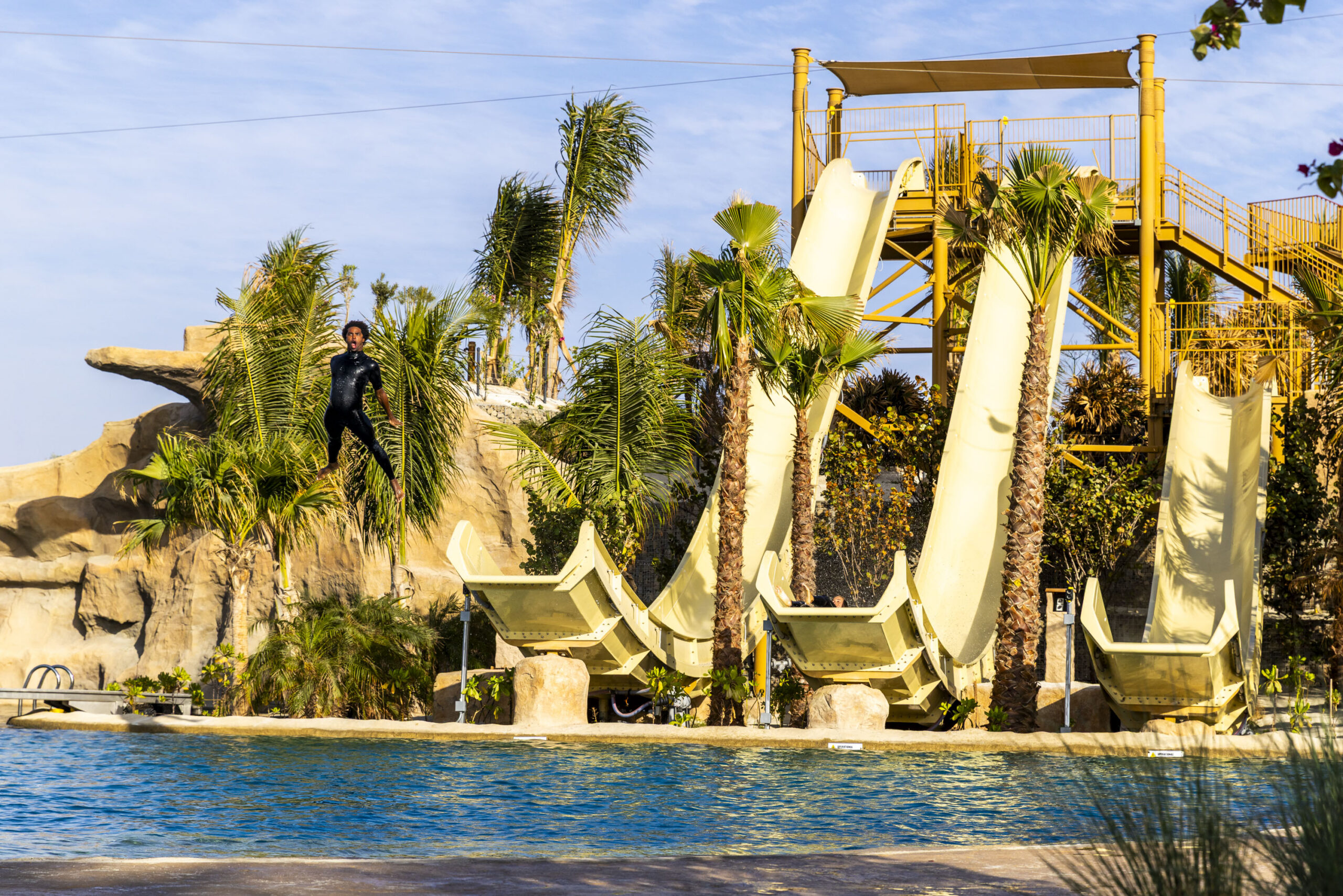 Man flying off one of three beige water slides