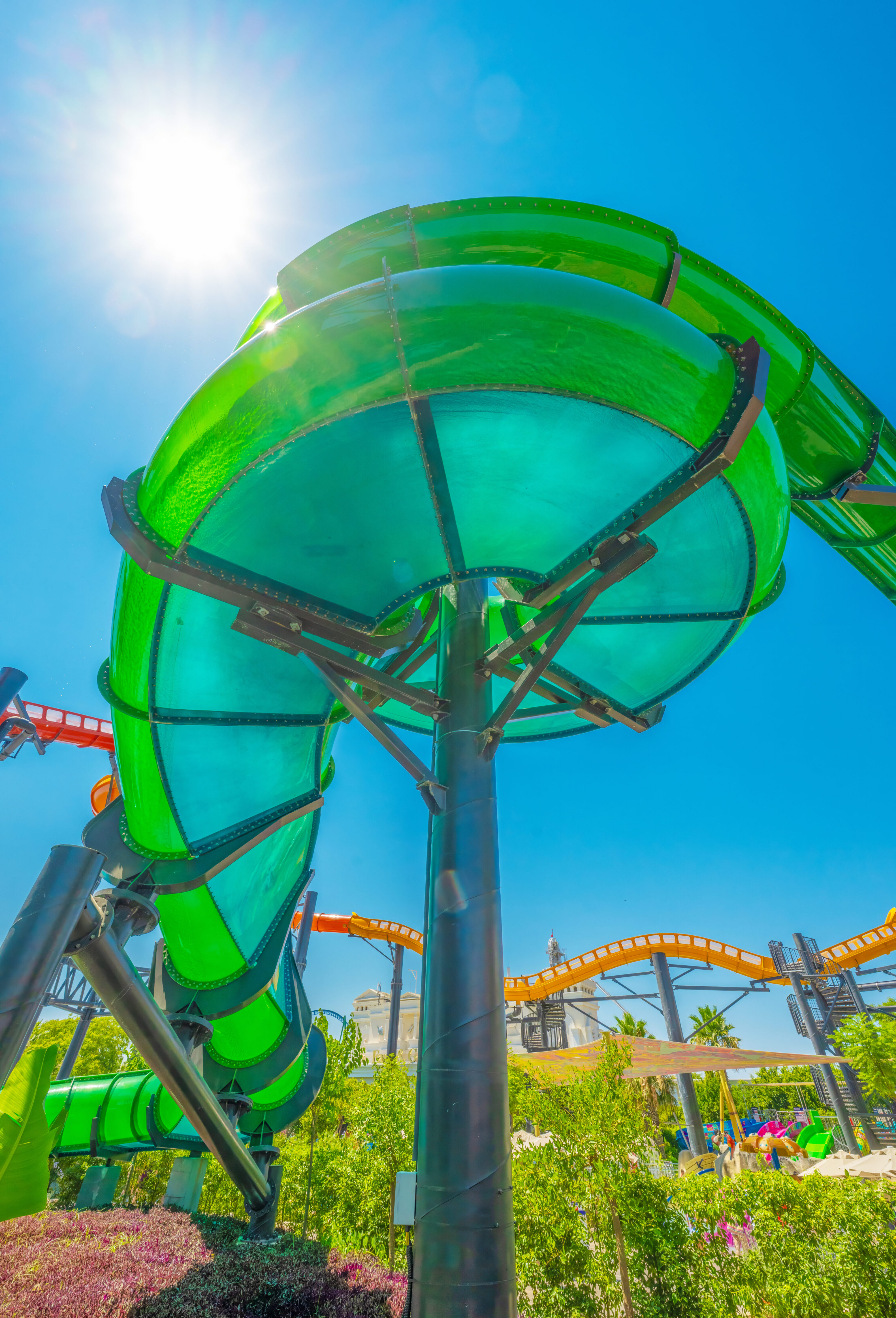 A green water slide flume against blue sky