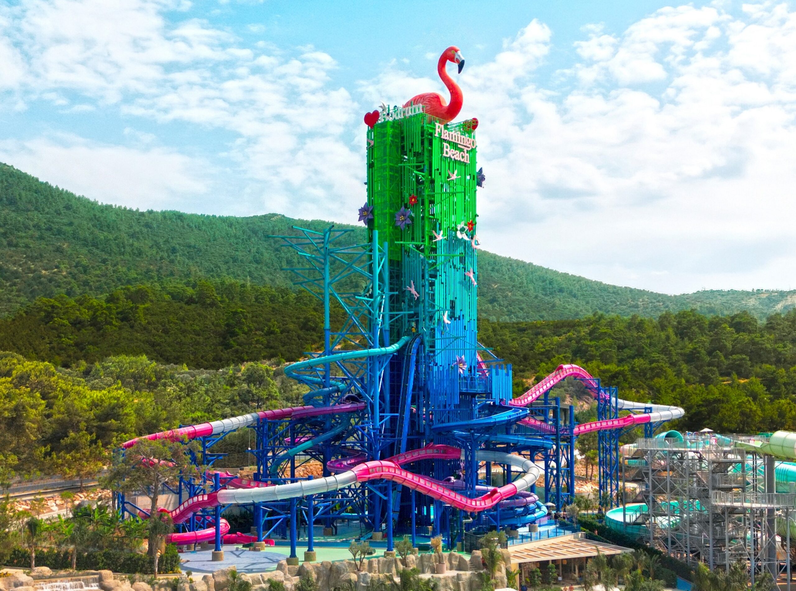 A tall water slide tower with a pink flamingo on top