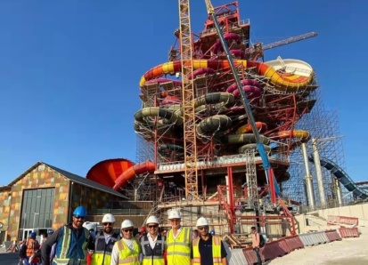 A group of men in front of a water slide tower under construction