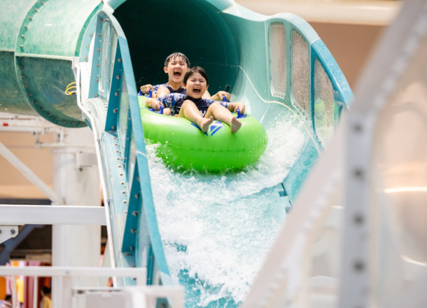 Two boys in an inner tube screaming while riding a water coaster