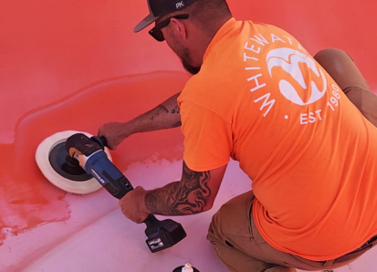A man in an orange shirt holding a buffer buffing a water slide